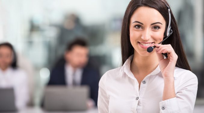 Portrait of happy smiling female customer support phone operator at workplace.